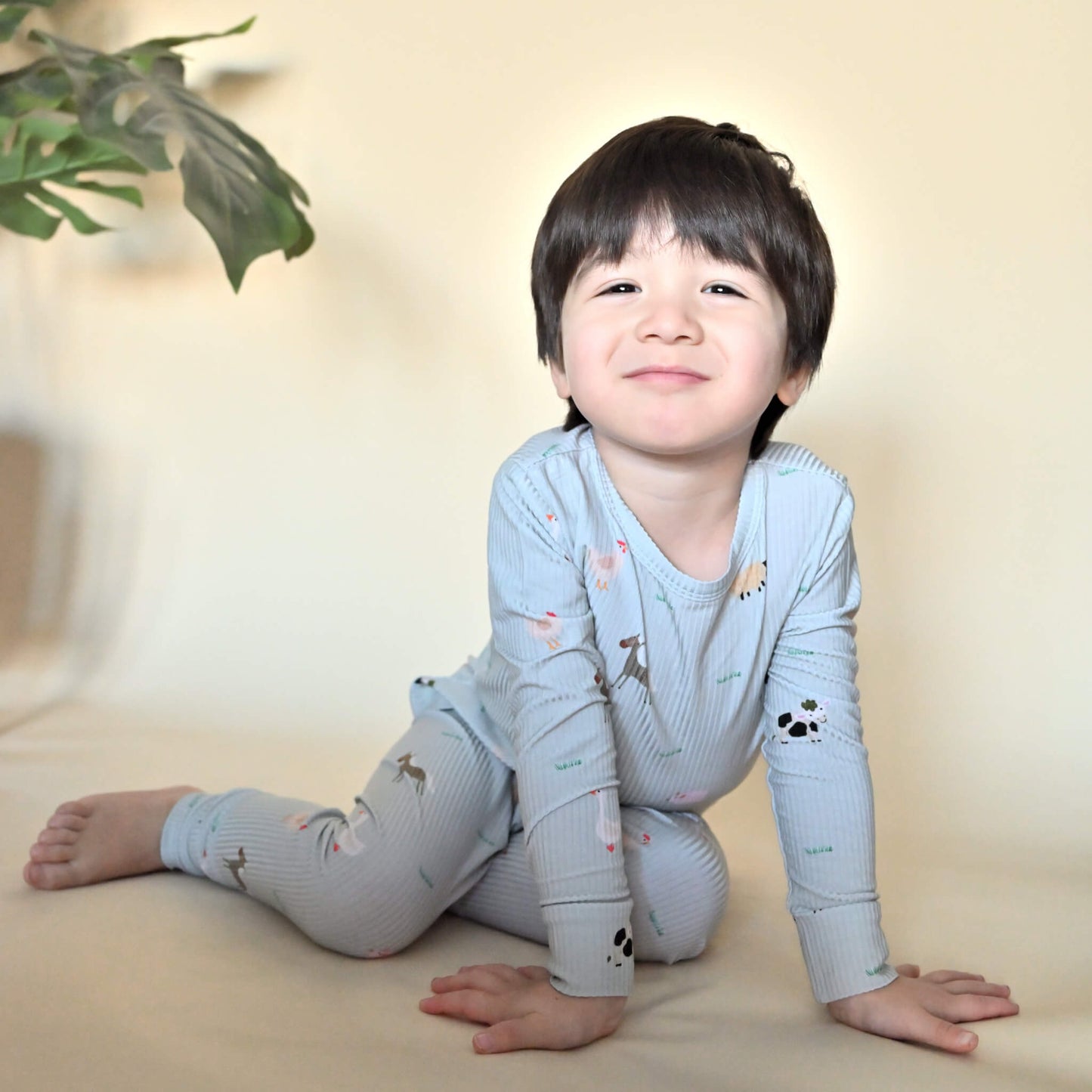 toddler boy in farm animal pattern pajamas smiling at camera