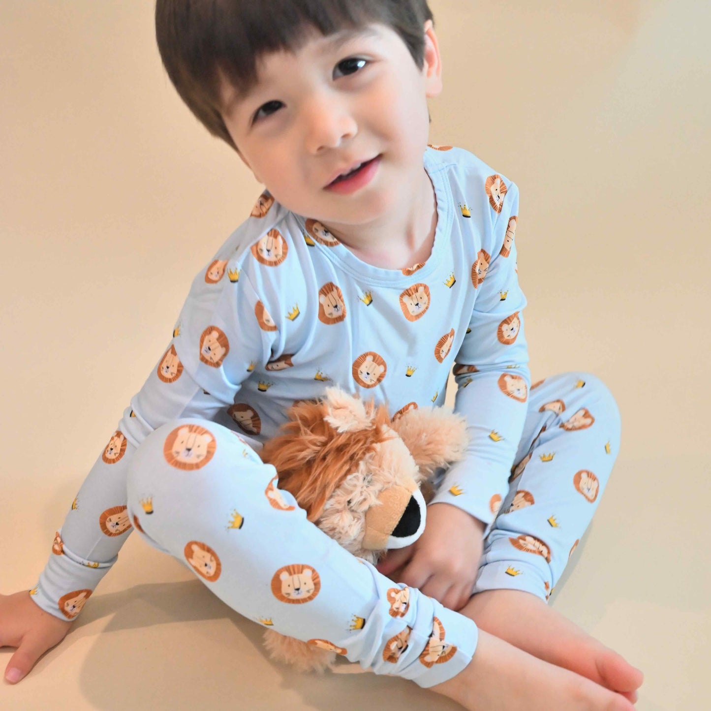 toddler wearing lion print pajamas holding stuffed lion