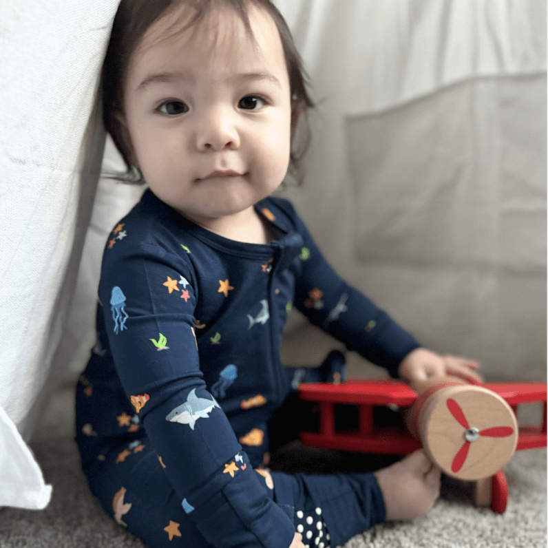 baby boy in sea animal print zip romper looking at camera