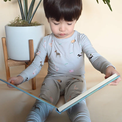 toddler boy in farm animal pattern pajamas reading a board book
